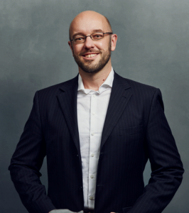 Meet the Team of experts - Photo of Carsten Krüger, person in business suit, glasses with dark frames, smiling, male, gallantly, standing upright