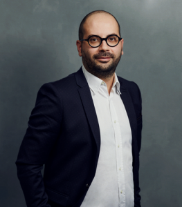 Meet the Team of experts - Photo of Danilo Samà, person in business suit, glasses with dark frames, smiling, male, gallantly, standing upright